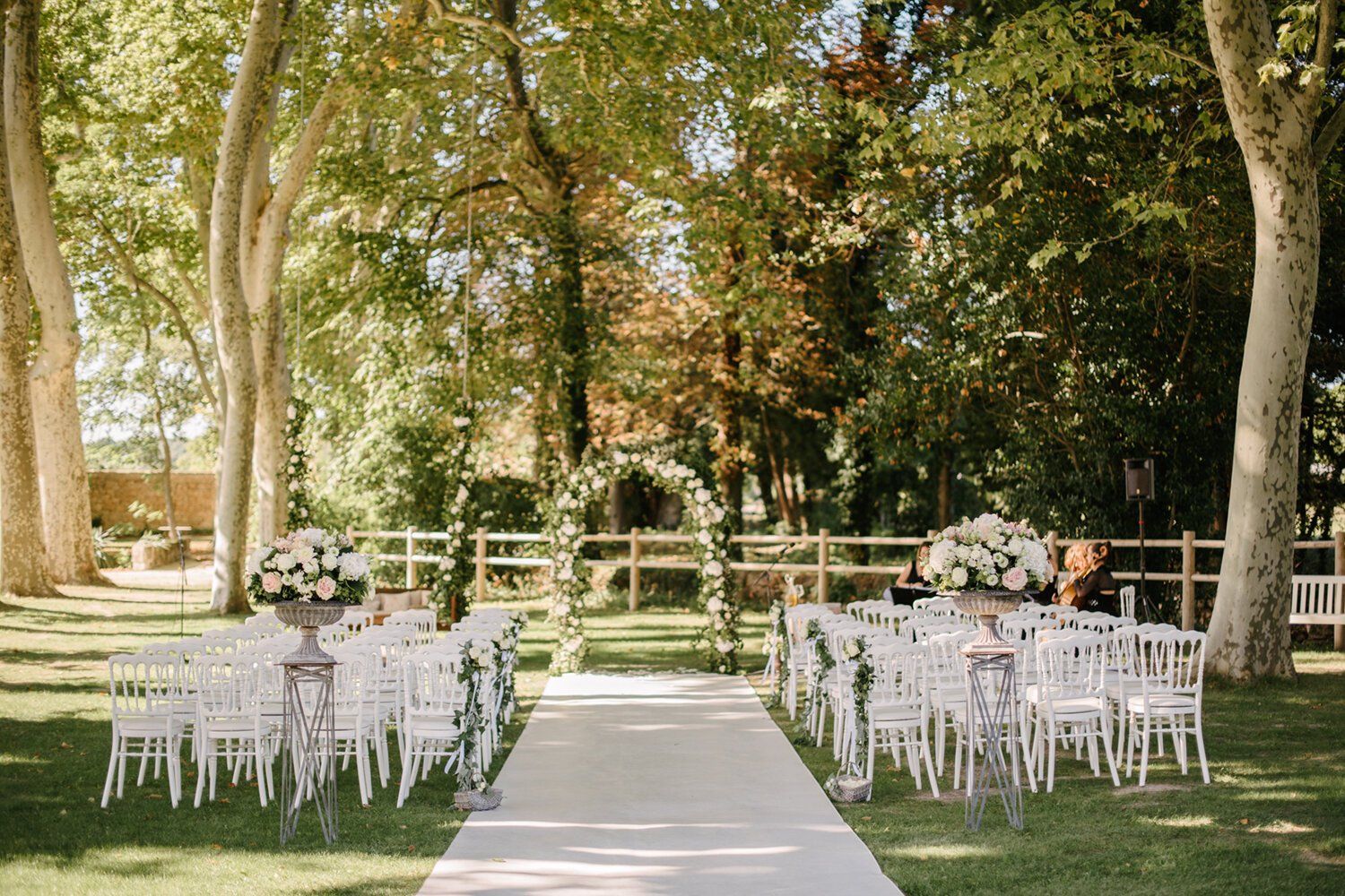 Cérémonie de mariage en extérieur avec chaises blanches, fleurs et arche végétale