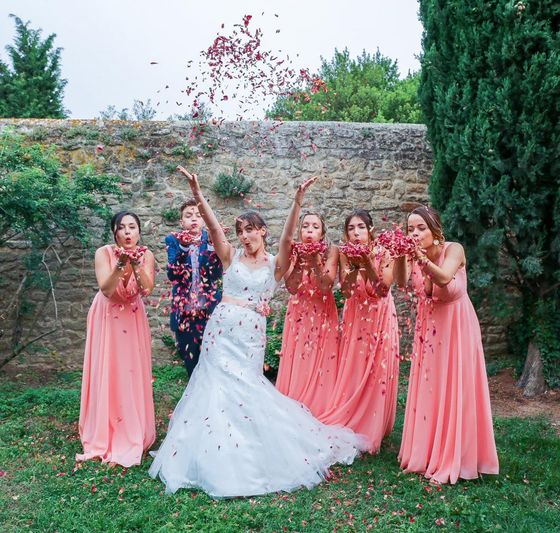 Mariée et demoiselles d’honneur lançant des pétales de fleurs séchés lors d’un mariage