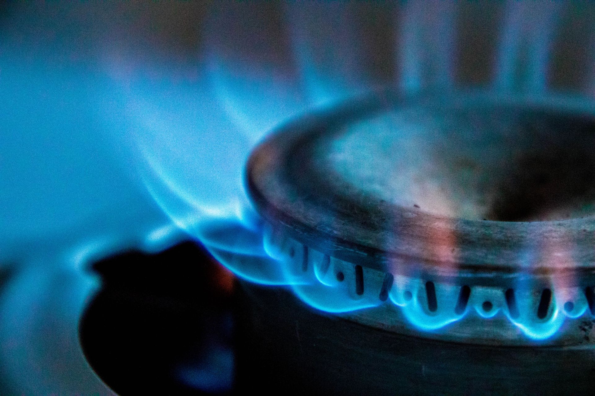 Close-up of blue gas flame burning on a kitchen stove burner.