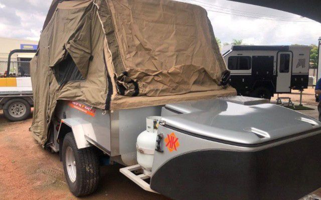 A Trailer With A Tent On Top Of It Is Parked In A Parking Lot — Ozzie Camper Trailers in Aitkenvale, QLD