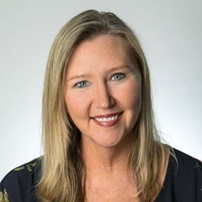 Smiling woman with blonde hair in a dark top against a light background