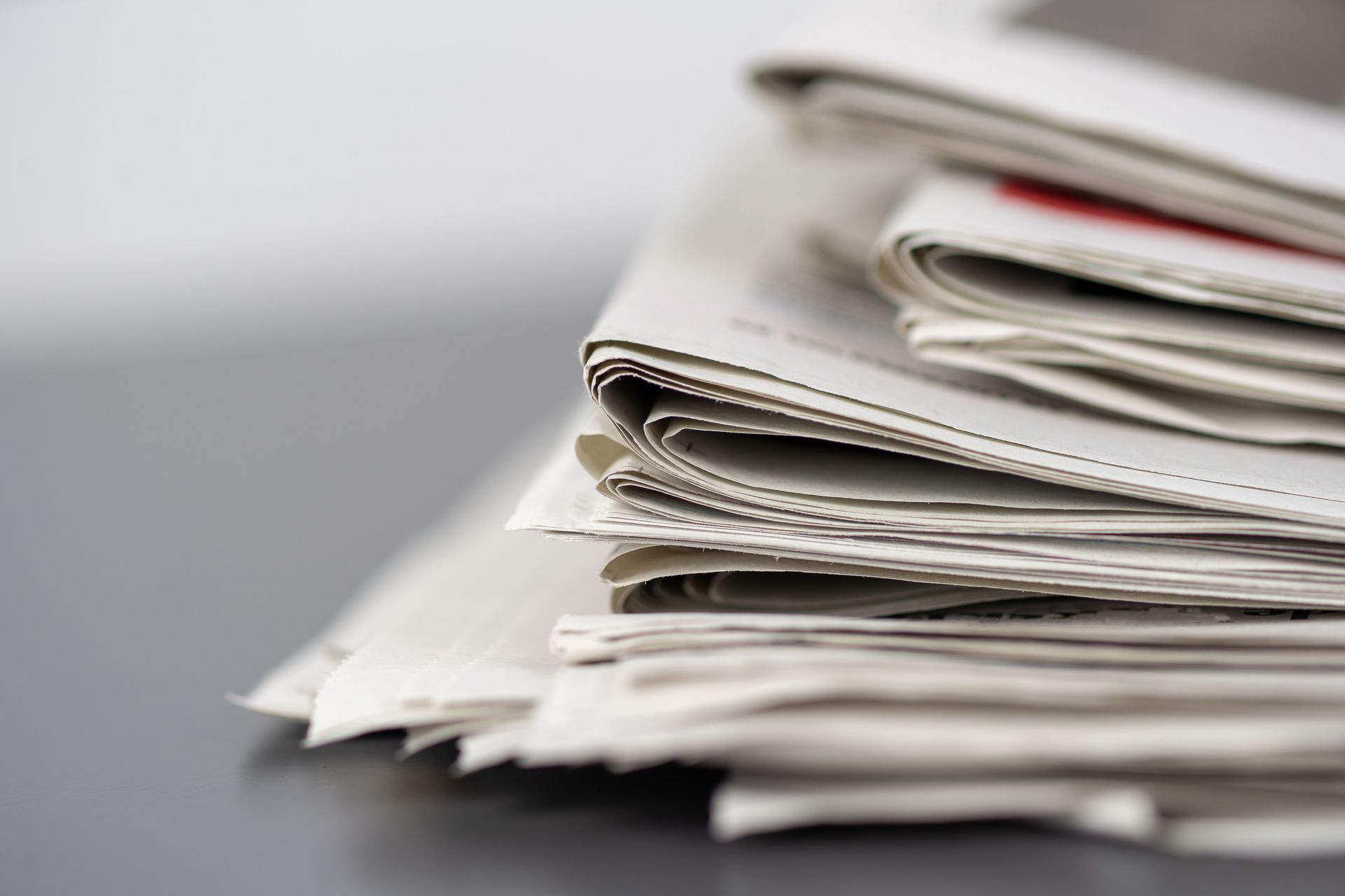 Stack of folded newspapers or magazines on a gray surface
