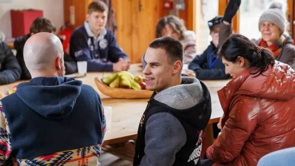 A group of people are sitting around a table talking to each other.