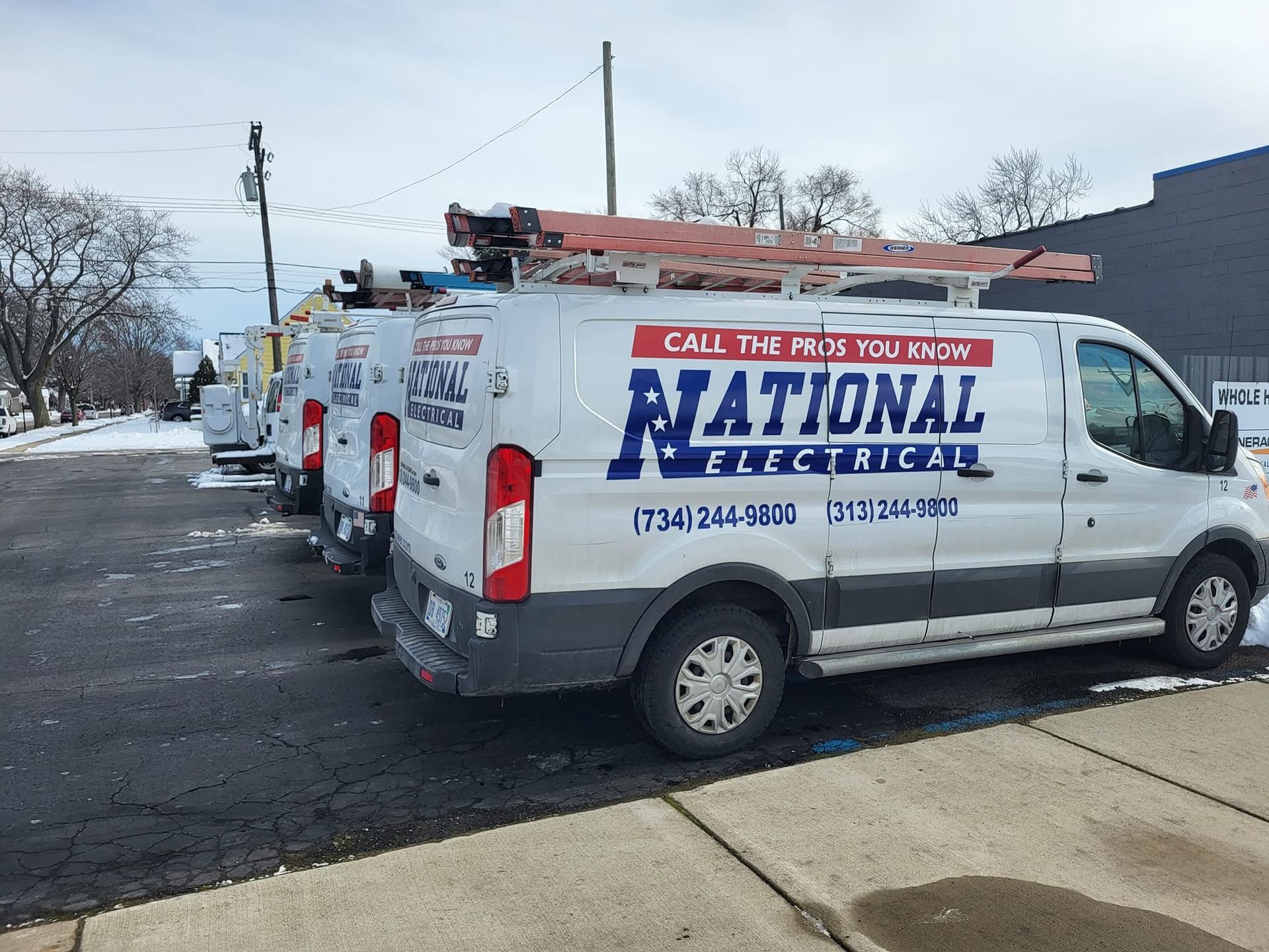 White National Electric vans parked outside a building with snow on the ground and roof.