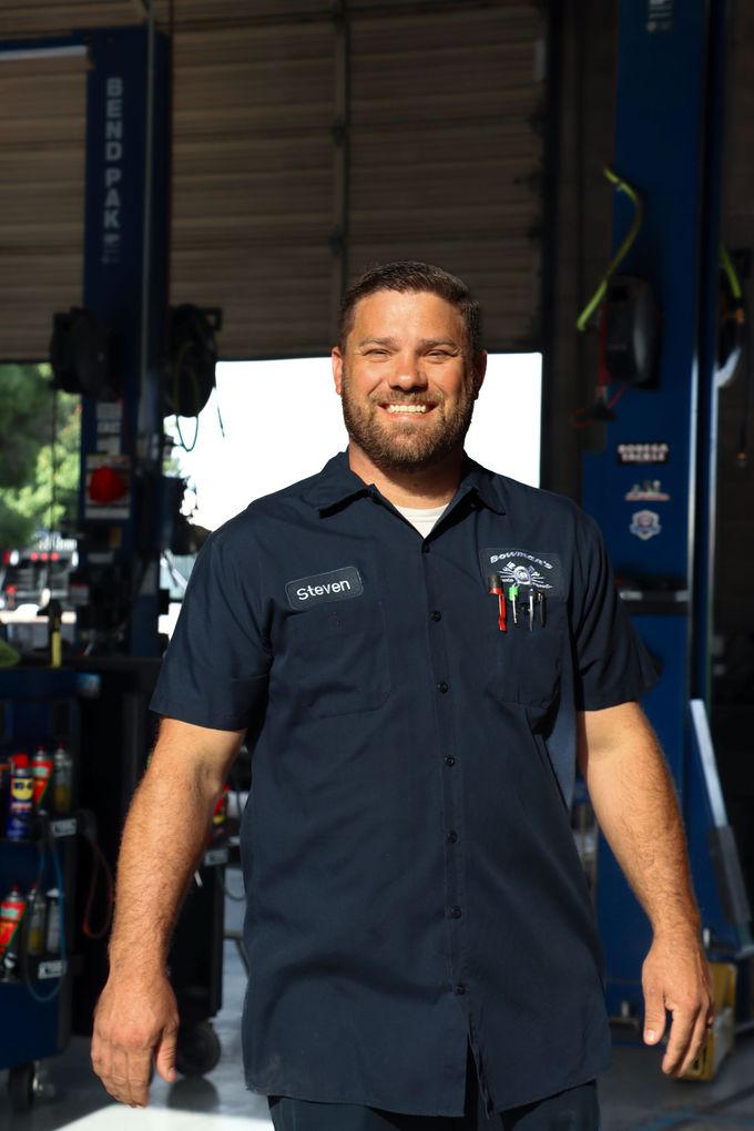A man in a blue shirt is standing in a garage.