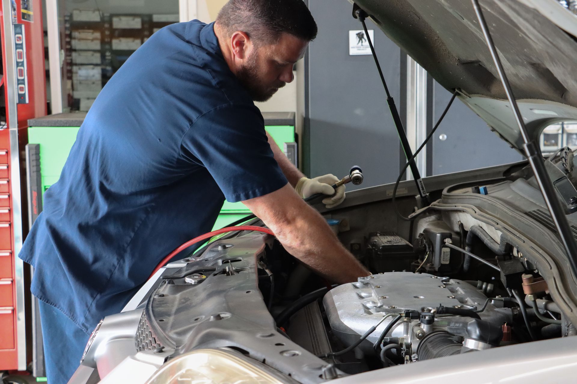 A man is working on the engine of a car in a garage.