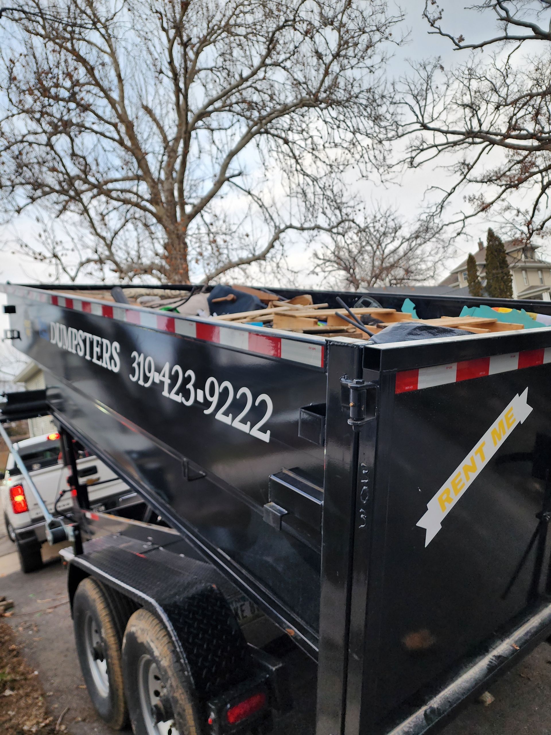 Black dumpster on a trailer with waste.