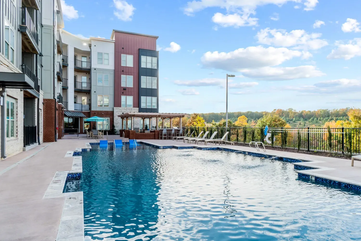 Swimming pool and lounge area with apartment buildings in the background.