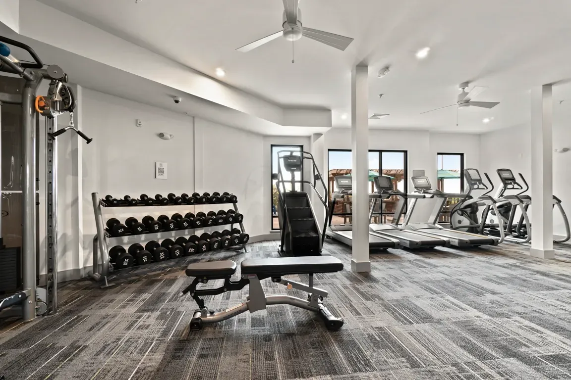 Gym with treadmills, stair climber, weight rack with dumbbells, and a weight bench.
