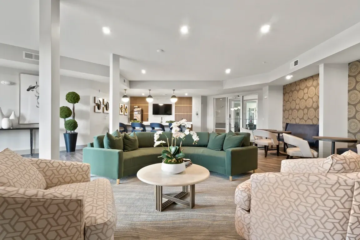Modern lounge area with curved green sofa, patterned armchairs, and coffee table.
