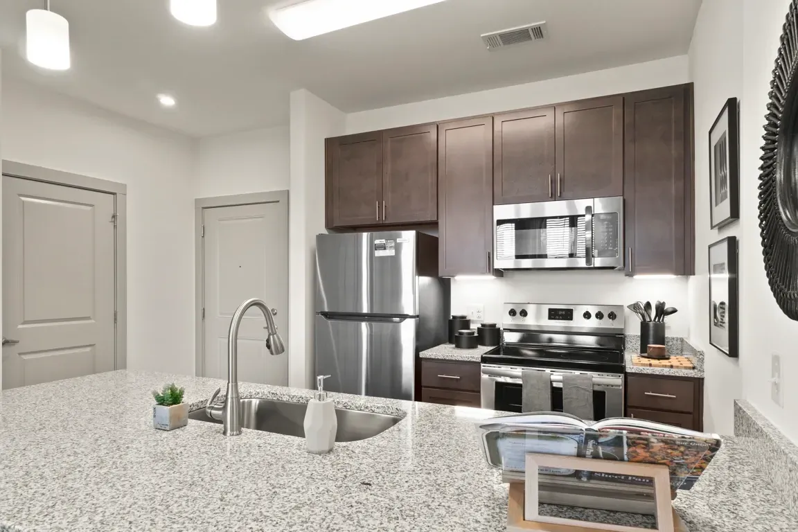Modern kitchen with stainless steel appliances, granite countertops, and dark wood cabinets.