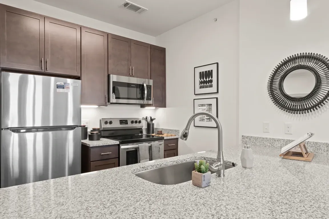 Modern kitchen with stainless steel appliances, granite countertops, and dark wood cabinets.