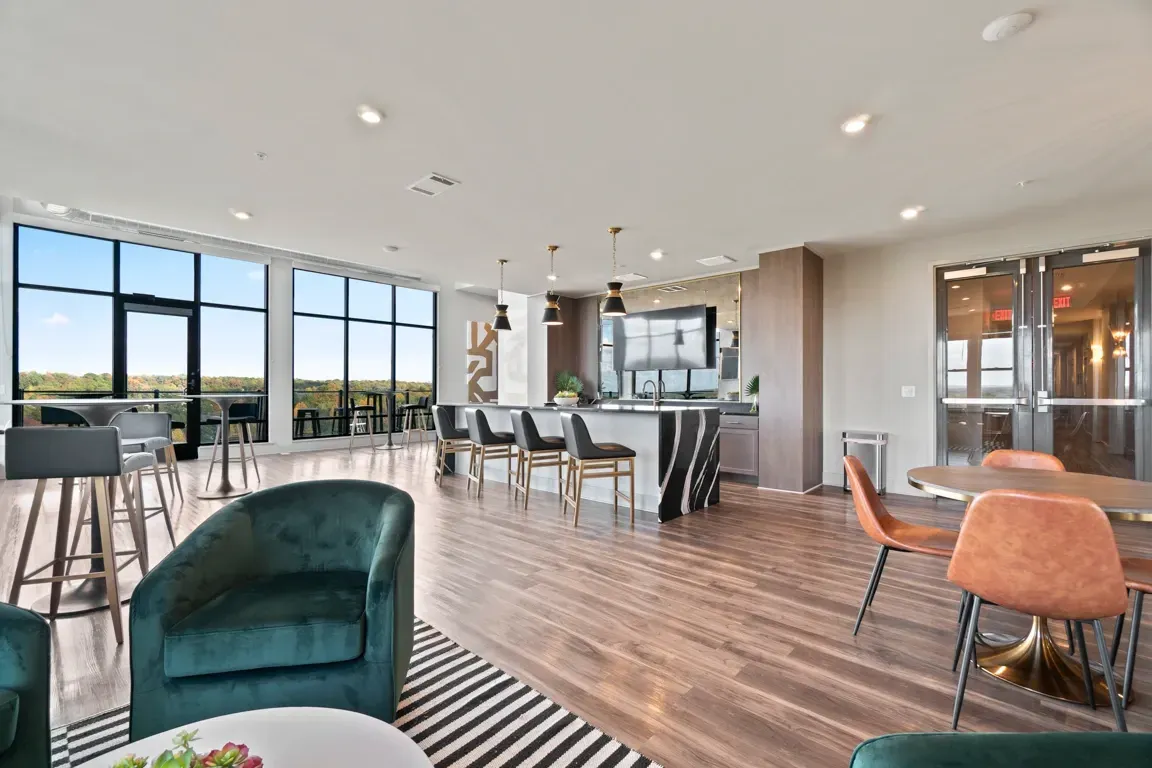 Spacious lounge area with modern seating, a full-service bar, and panoramic city views.