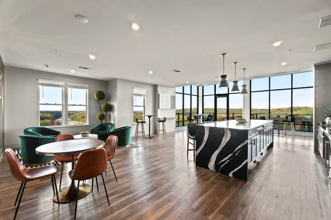 Modern community lounge area with a large island, seating, and city views.