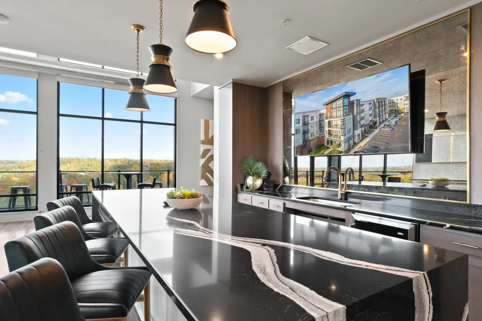 Modern apartment kitchen island with bar stools and large windows with scenic view.