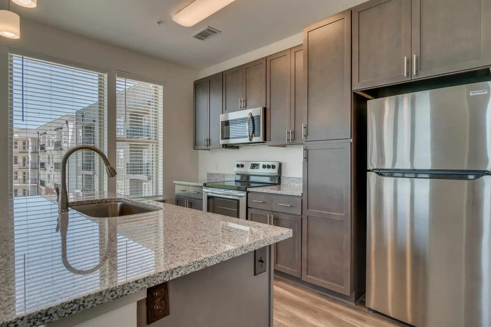 Modern kitchen with granite island, stainless steel appliances, and city view through large windows