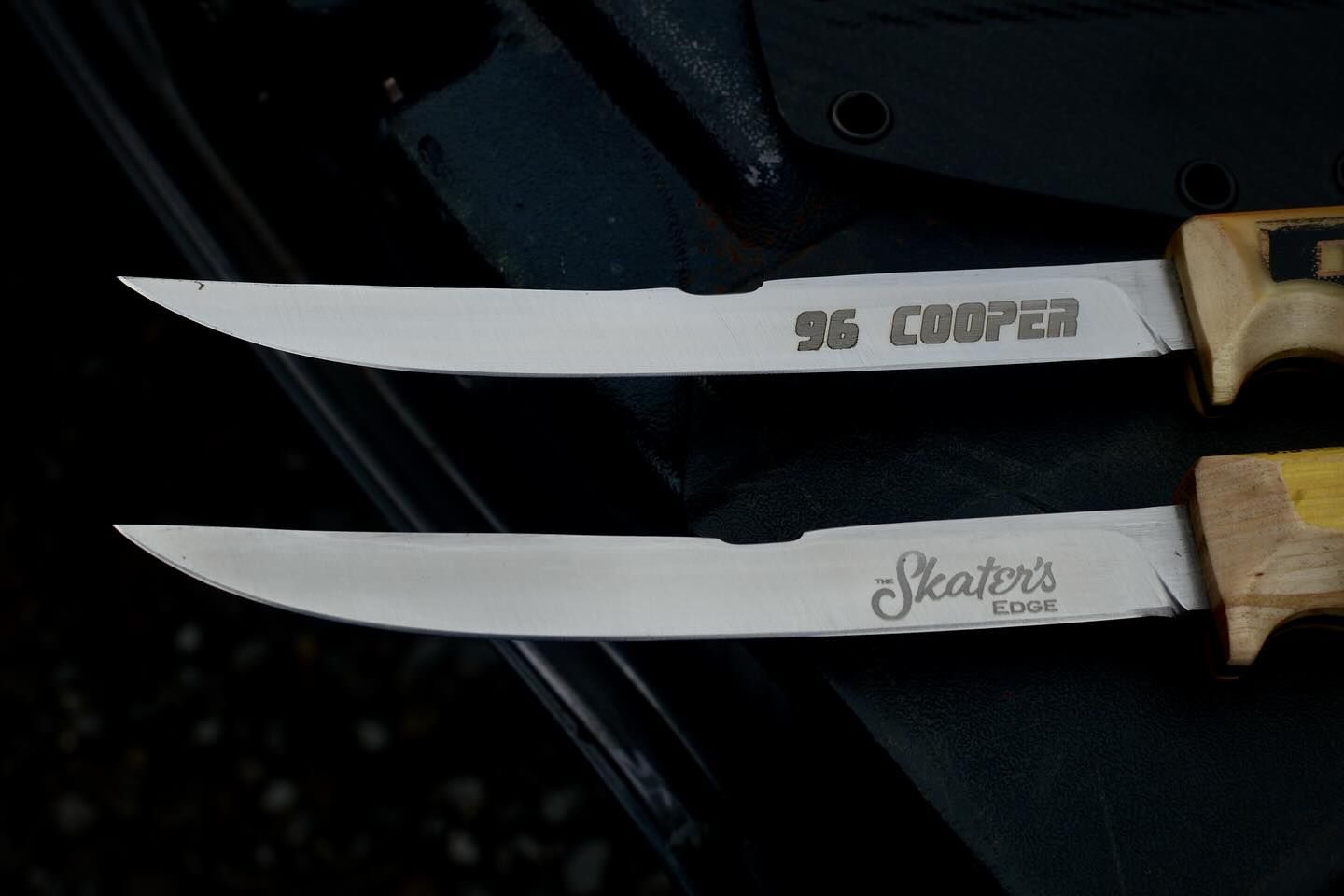 Two knives with wooden handles and curved blades; one says