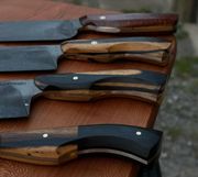 Close-up of four knives with wooden handles, displayed on a brown surface.