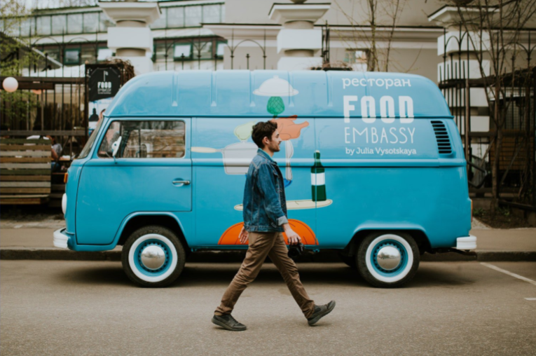 Man walks past a blue food truck,