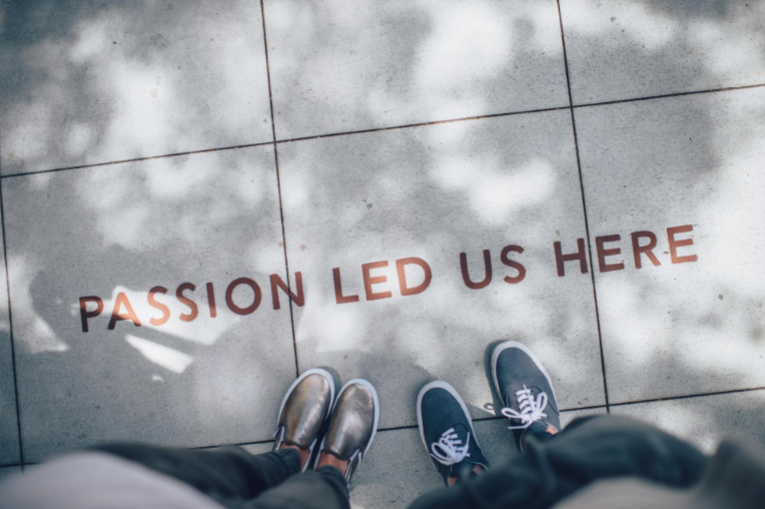 Two pairs of feet standing on a tiled surface with the words 