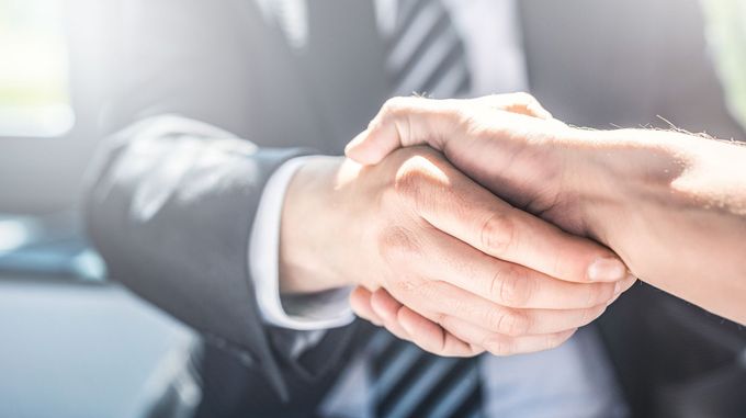 Due persone che si stringono la mano in un luminoso ufficio.