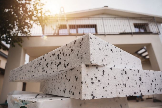 Blocchi di cemento bianco screziato impilati all'aperto di fronte a un edificio moderno al tramonto
