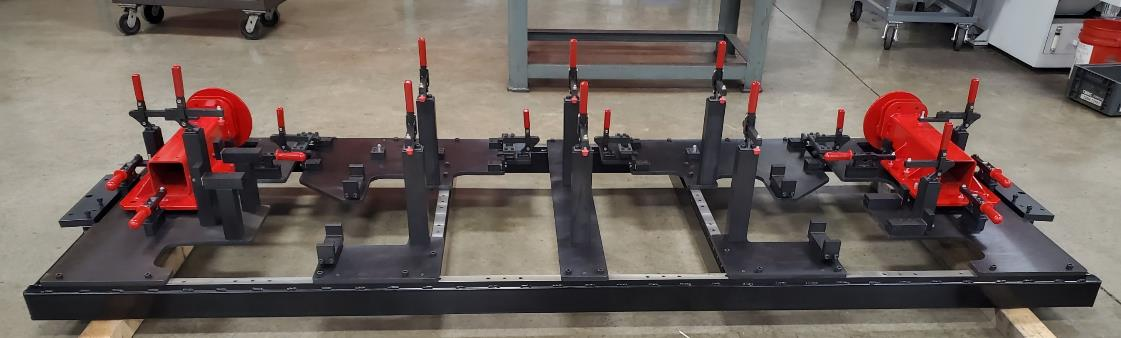 Metal fabrication jig with red and black components. For industrial use, possibly welding.