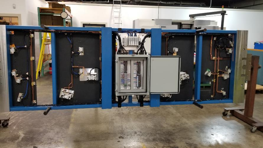 Large blue industrial control panel with wiring and components on a factory floor.
