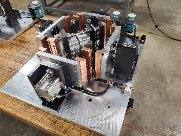 Complex industrial machine on a metal plate, featuring various components, wiring, and a copper-colored element.