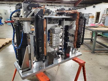 Industrial machine with copper components, mounted on a stand in a workshop.