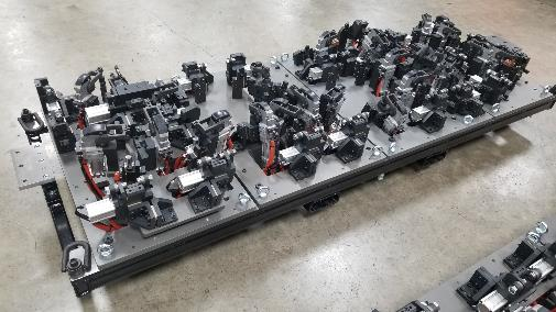 A complex optical setup on a metal platform, consisting of various black components and lenses.