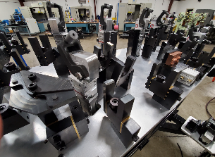 Metal fixtures on a manufacturing table in a workshop, possibly for holding parts during machining.