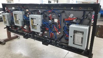 Panel with electronic components and wiring, mounted in a black frame, indoors.