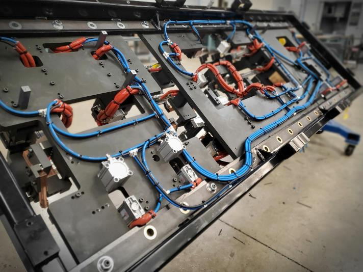 Metal frame with blue and red wiring harnesses, containing electrical components.