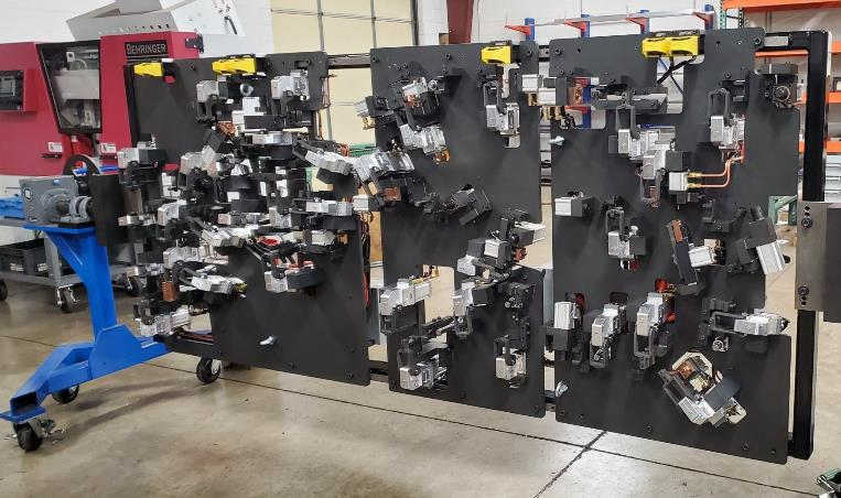 Assembly fixture with numerous components mounted on black panels, likely for manufacturing.