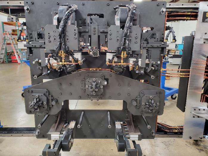 Black industrial machine with copper tubing, used in a manufacturing setting.