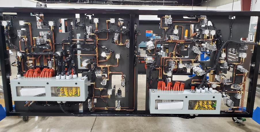 Two connected electrical panels with copper tubing, wiring, and circuit breakers.