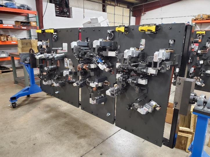 Large industrial fixture with multiple mounted parts, likely for manufacturing, in a workshop setting.