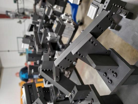 A collection of black metal machine parts, likely for industrial use, with a person in the background.