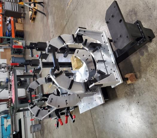 Machining fixture with multiple clamping arms, likely for holding workpieces in a workshop setting.