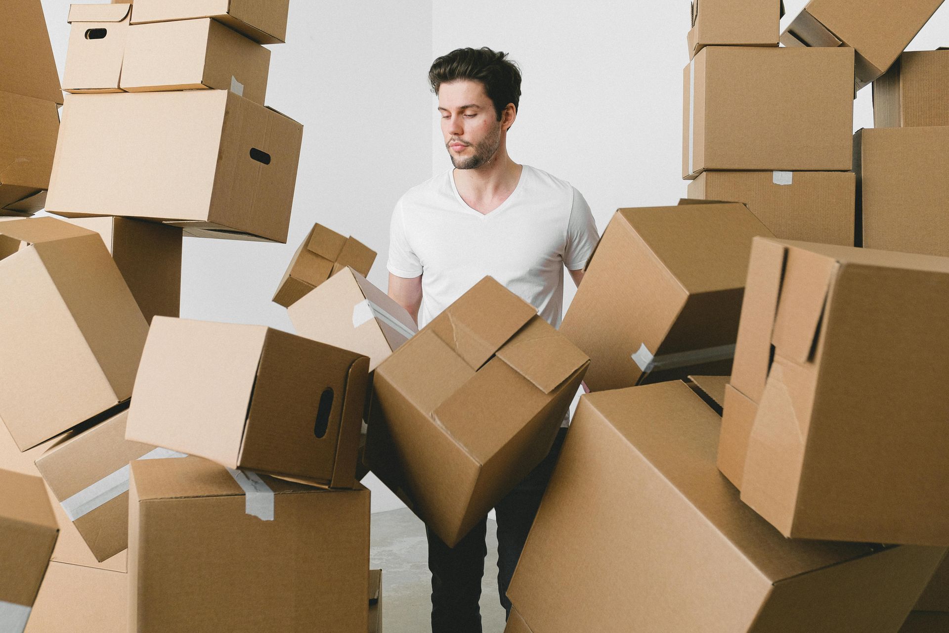 A man is standing in front of a pile of cardboard boxes.