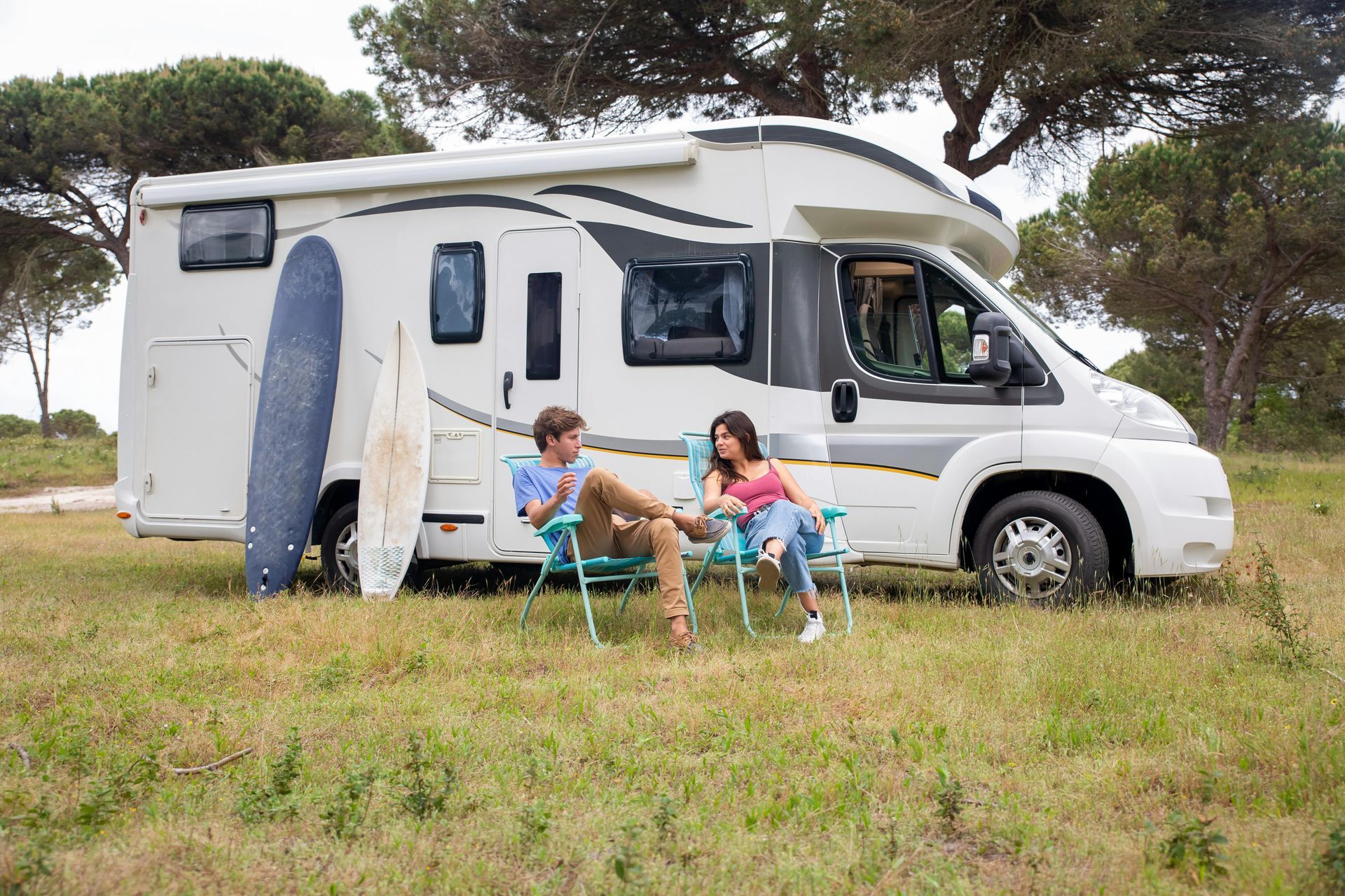 A man and a woman are sitting in chairs in front of a rv.