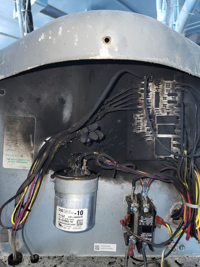 Open appliance interior with wiring, a silver canister, and control components under a gray metal cover