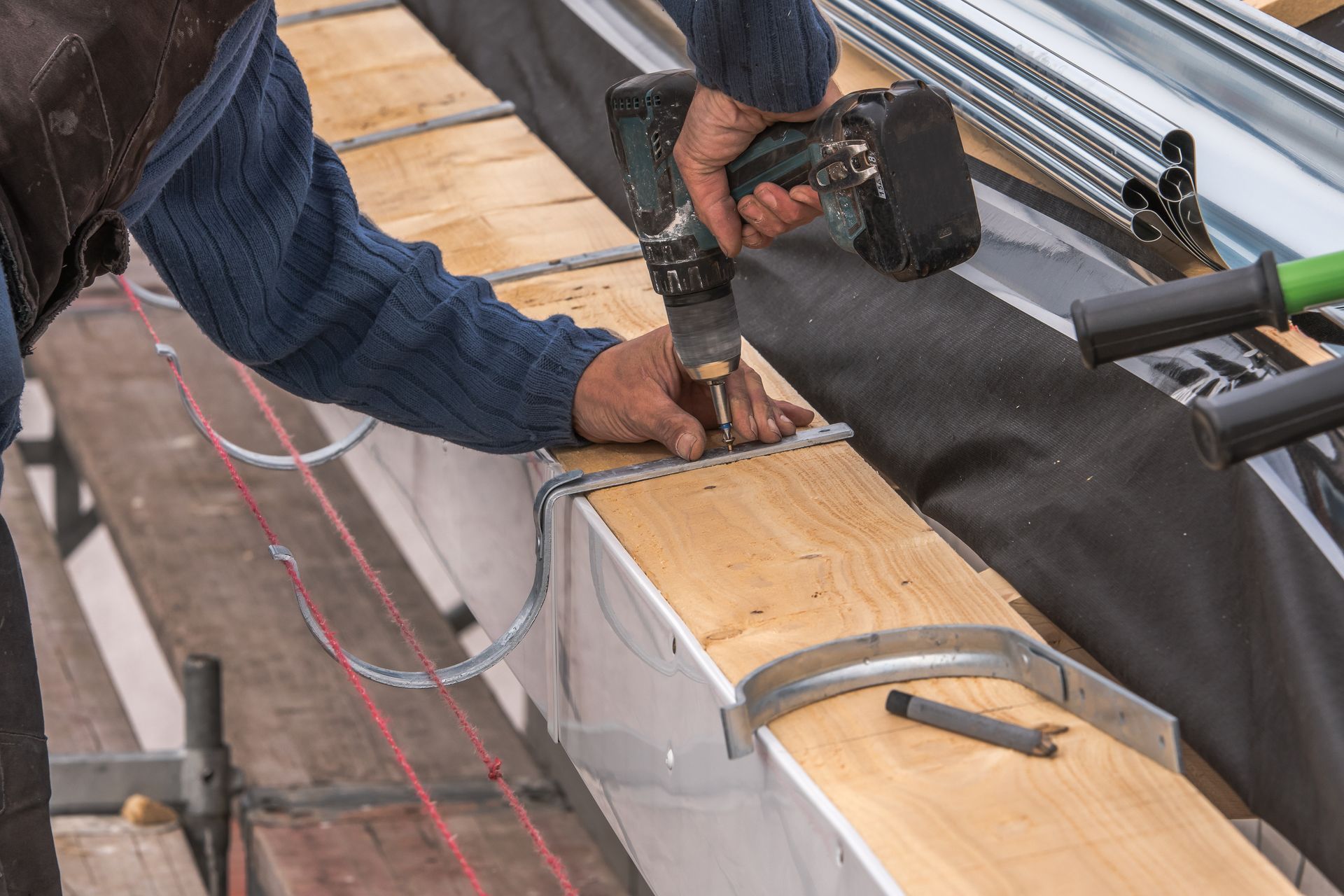 Worker fastening wooden beams on a roof with a nail gun and hand tools Worker fastening wooden beams on a roof with a nail gun and hand tools