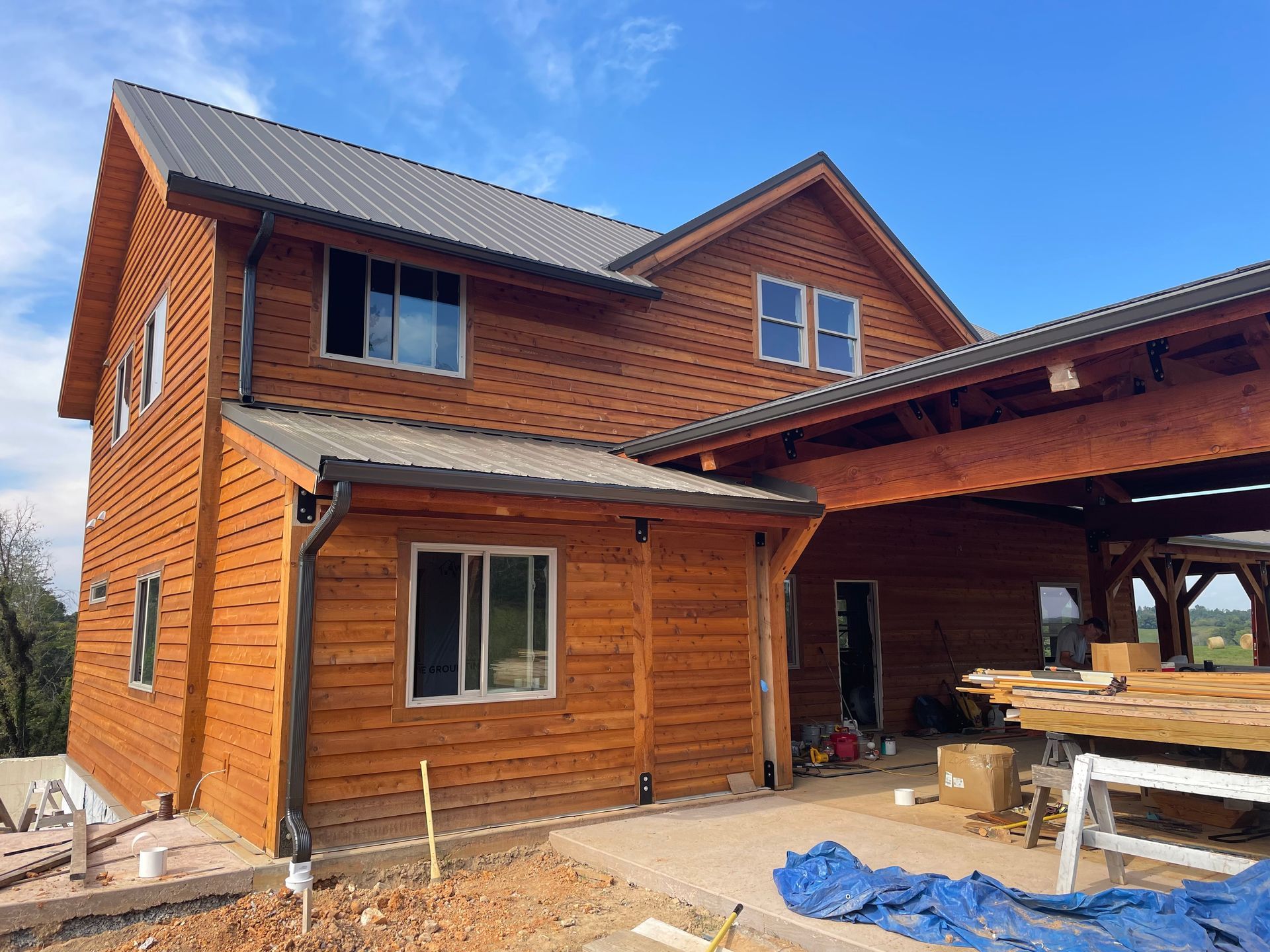 Two-story wooden house under construction with brown siding and an attached covered porch.