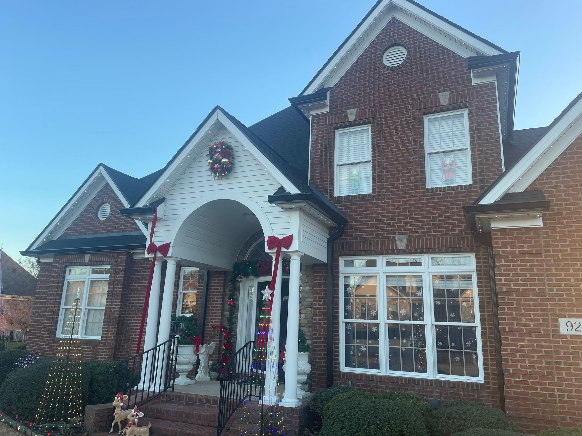 Brick house with white trim and arched entryway, decorated with holiday wreaths and garlands