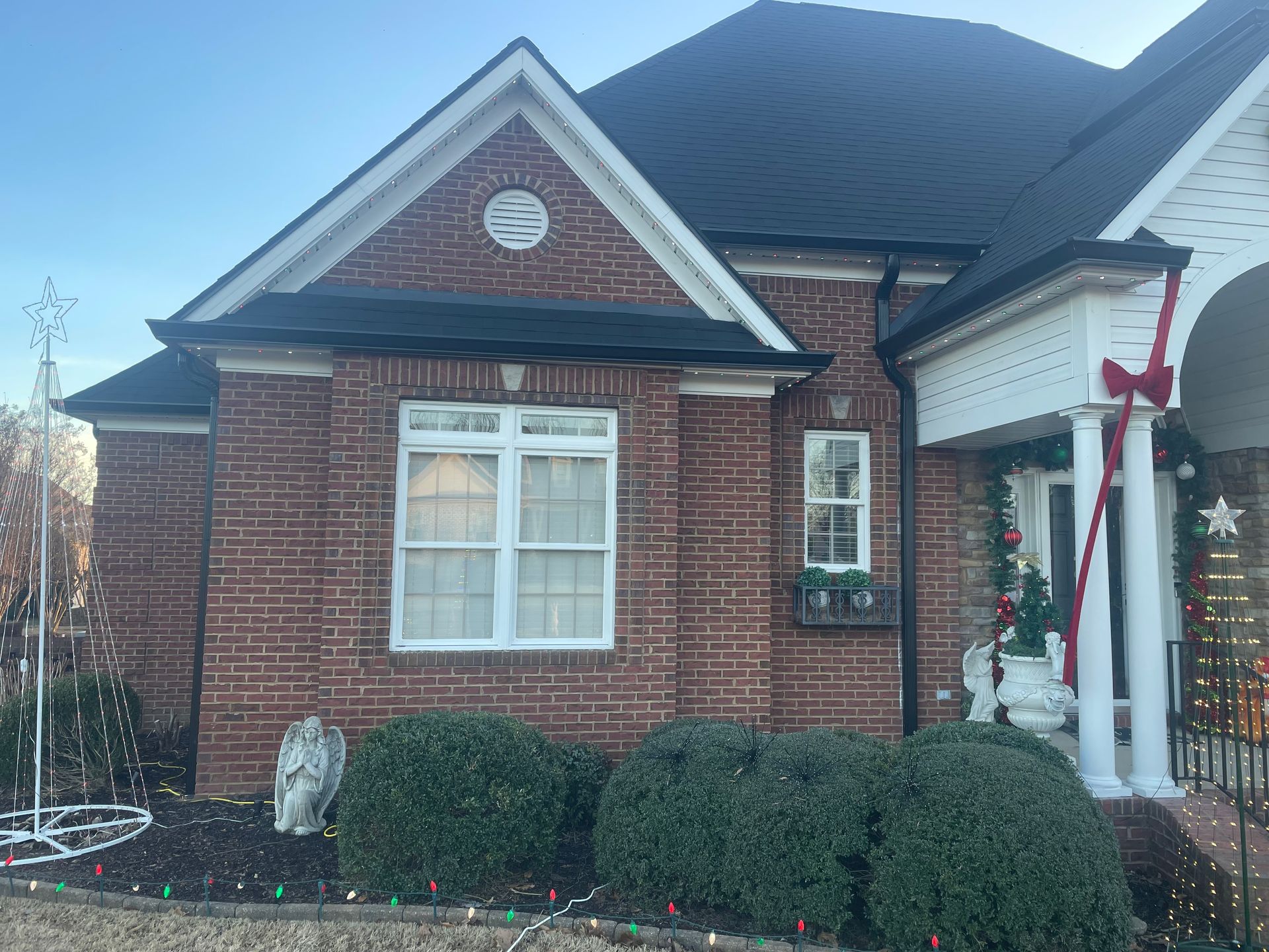 Brick house with white trim and holiday decorations, including a wreath and porch ornaments.