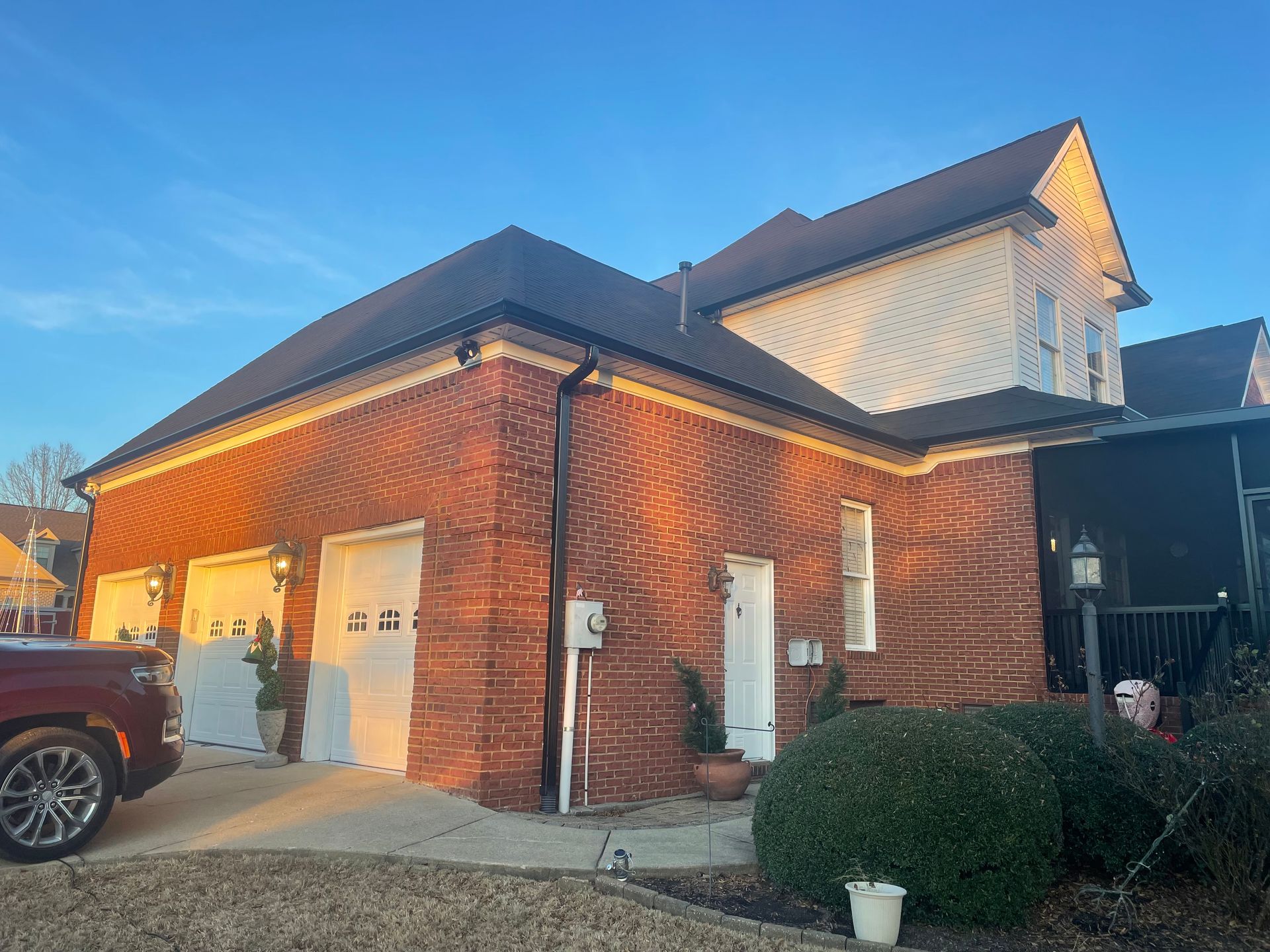 Brick house exterior with driveway, garage, and parked truck in warm evening light