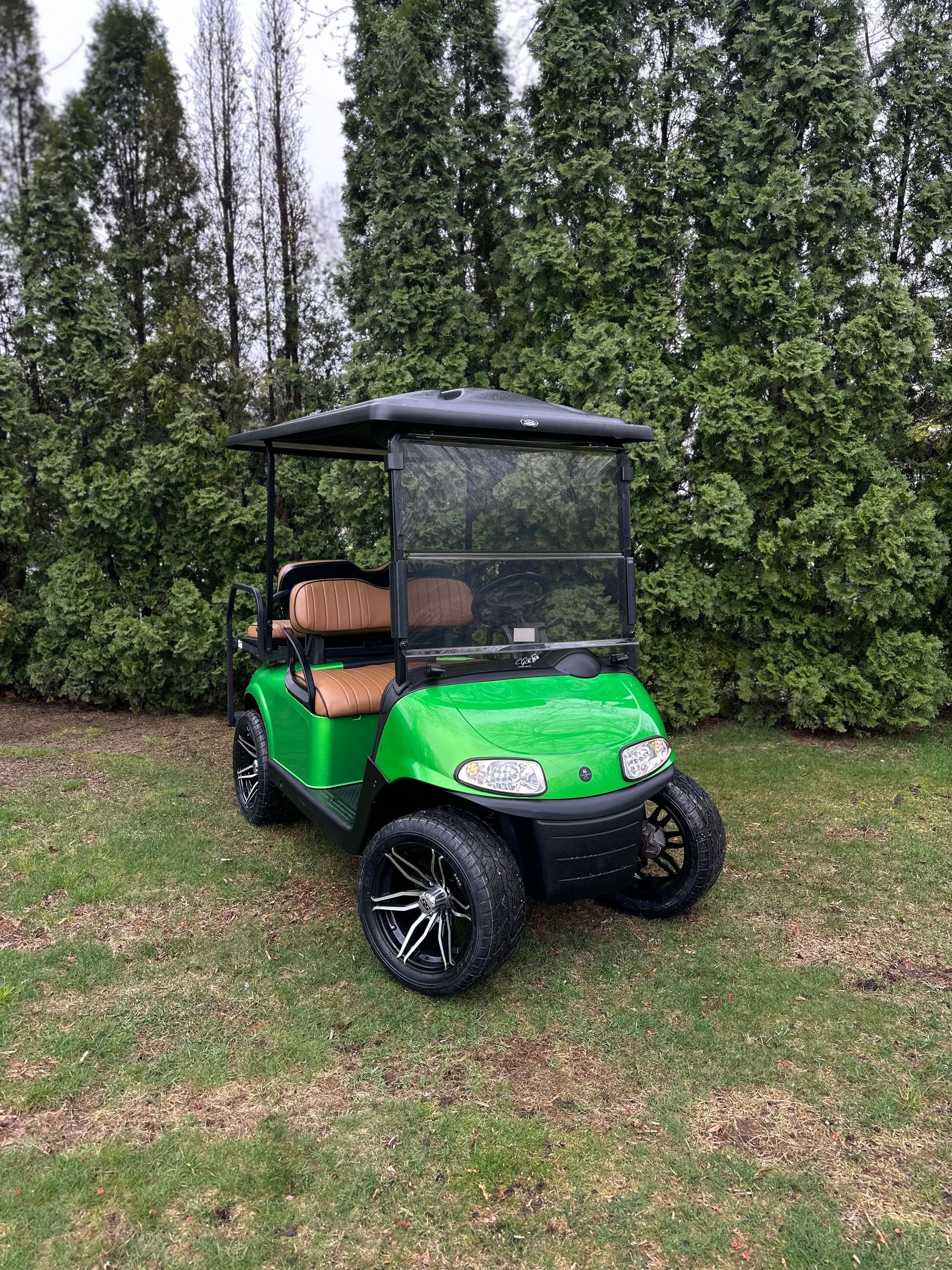 A green golf cart is parked in a grassy field.