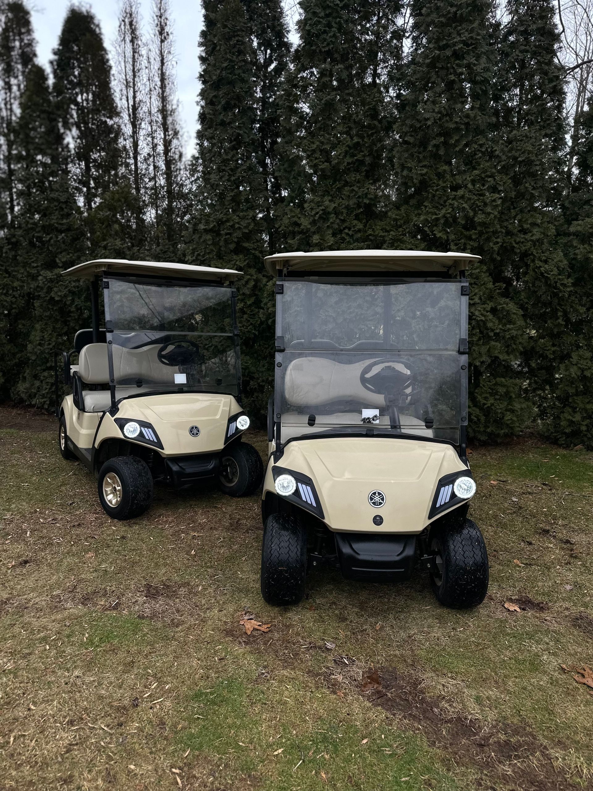 Two golf carts are parked next to each other in a grassy field.